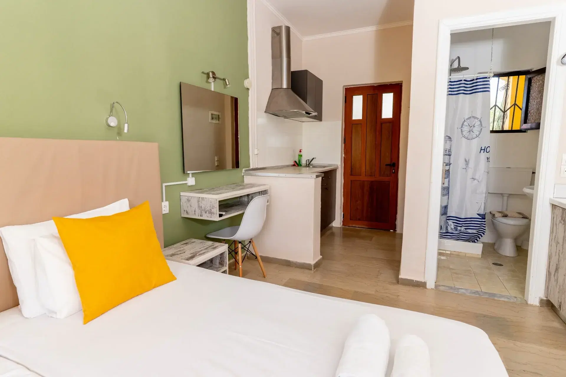 Apartman belső tere: ágy, konyhasarok és mögötte a zuhanyzó